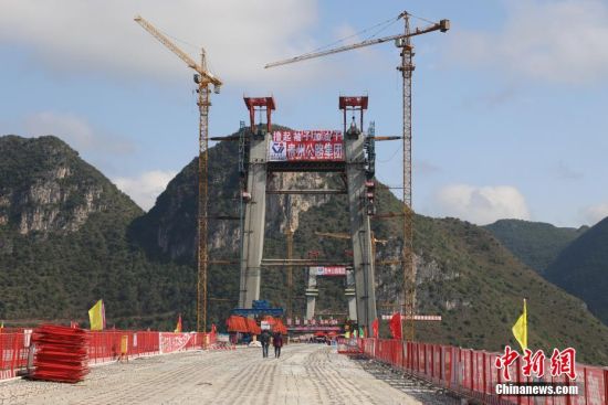 11月22日，正在建設(shè)中的峰林特大橋。當日，隨著1470噸裝配化預制中橫梁提升到位，貴州省黔西南布依族苗族自治州興義環(huán)城高速公路峰林特大橋4號主塔中橫梁成功吊裝，由此刷新了山區(qū)峽谷橋梁預制吊裝混凝土構(gòu)件重量世界記錄。峰林特大橋是屬全線控制性工程。大橋跨越馬嶺河峽谷，全長1163米，主跨采用550米懸索橋，橋面離谷底364.2米，是中國山區(qū)第一座大跨徑鋼混疊合梁懸索橋。中新社記者 瞿宏倫 攝