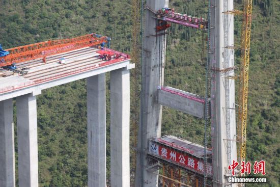 11月22日，峰林特大橋4號主塔中橫梁正在吊裝。當日，隨著1470噸裝配化預制中橫梁提升到位，貴州省黔西南布依族苗族自治州興義環(huán)城高速公路峰林特大橋4號主塔中橫梁成功吊裝，由此刷新了山區(qū)峽谷橋梁預制吊裝混凝土構(gòu)件重量世界記錄。峰林特大橋是屬全線控制性工程。大橋跨越馬嶺河峽谷，全長1163米，主跨采用550米懸索橋，橋面離谷底364.2米，是中國山區(qū)第一座大跨徑鋼混疊合梁懸索橋。中新社記者 瞿宏倫 攝