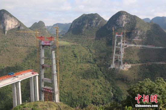 11月22日，正在建設(shè)中的峰林特大橋。當日，隨著1470噸裝配化預制中橫梁提升到位，貴州省黔西南布依族苗族自治州興義環(huán)城高速公路峰林特大橋4號主塔中橫梁成功吊裝，由此刷新了山區(qū)峽谷橋梁預制吊裝混凝土構(gòu)件重量世界記錄。峰林特大橋是屬全線控制性工程。大橋跨越馬嶺河峽谷，全長1163米，主跨采用550米懸索橋，橋面離谷底364.2米，是中國山區(qū)第一座大跨徑鋼混疊合梁懸索橋。中新社記者 瞿宏倫 攝